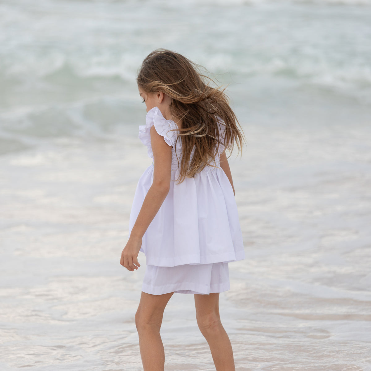 Henry Duvall girls smocked shorts set in Classic White, a classic two-piece outfit with flutter sleeves and blue embroidered smocking.