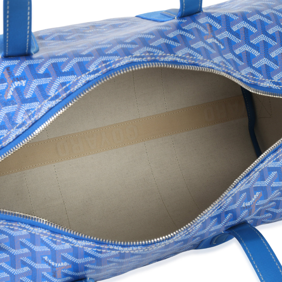 Top view of Goyardine Barrel 40 sports bag in sky blue showing open zip-top and beige interior lining with embossed Goyard strap