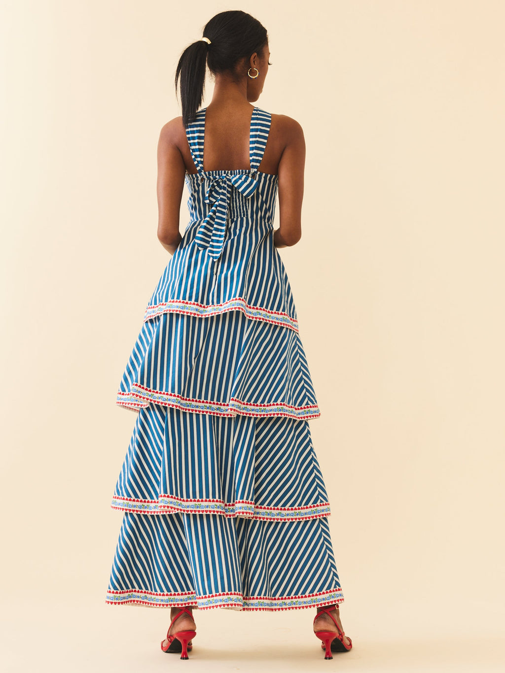 Rear view of Emma Dress in navy stripe showing back tie, smocked bodice, tiered maxi skirt with red trim on cream background