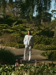 Front view of Isle Top in White Whimsy on model showcasing billowy long sleeves, embroidered eyelet details, and scalloped hem in a garden setting