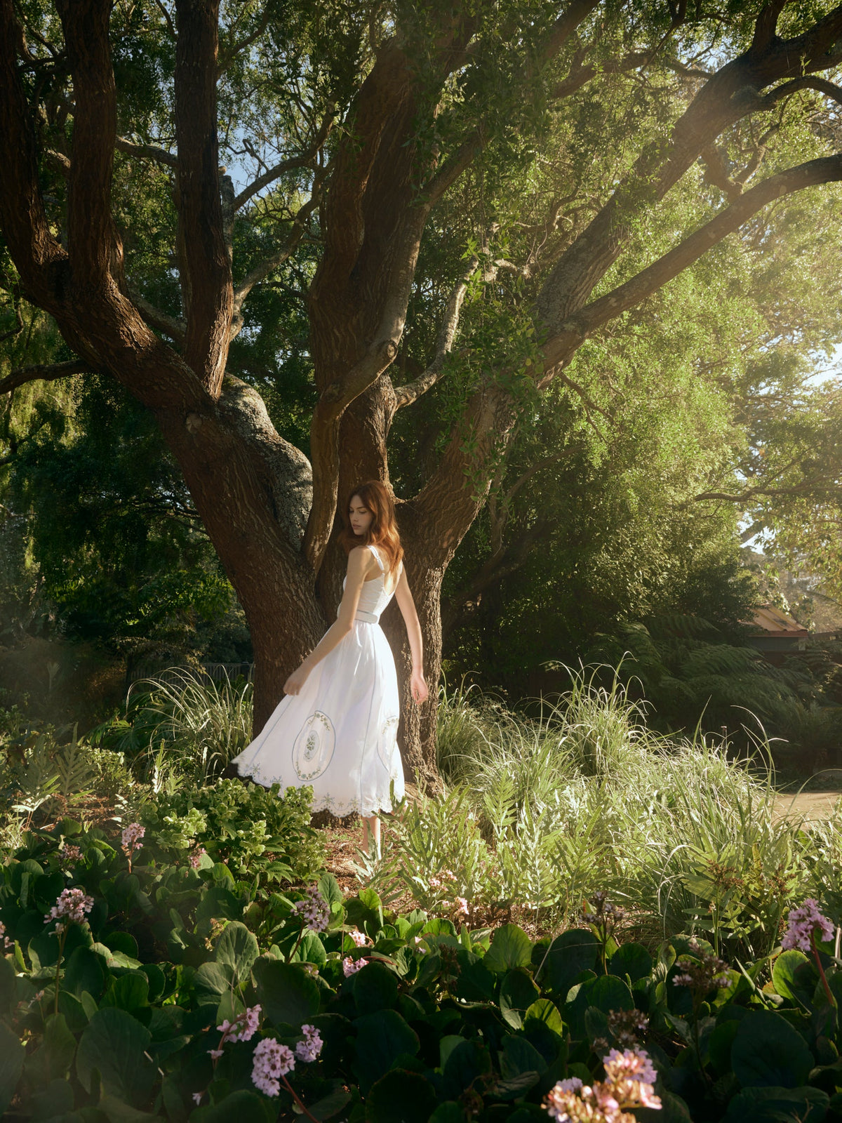 Back three-quarter view of Katherine dress in White Whimsy with embroidered A-line midi skirt and adjustable straps in garden