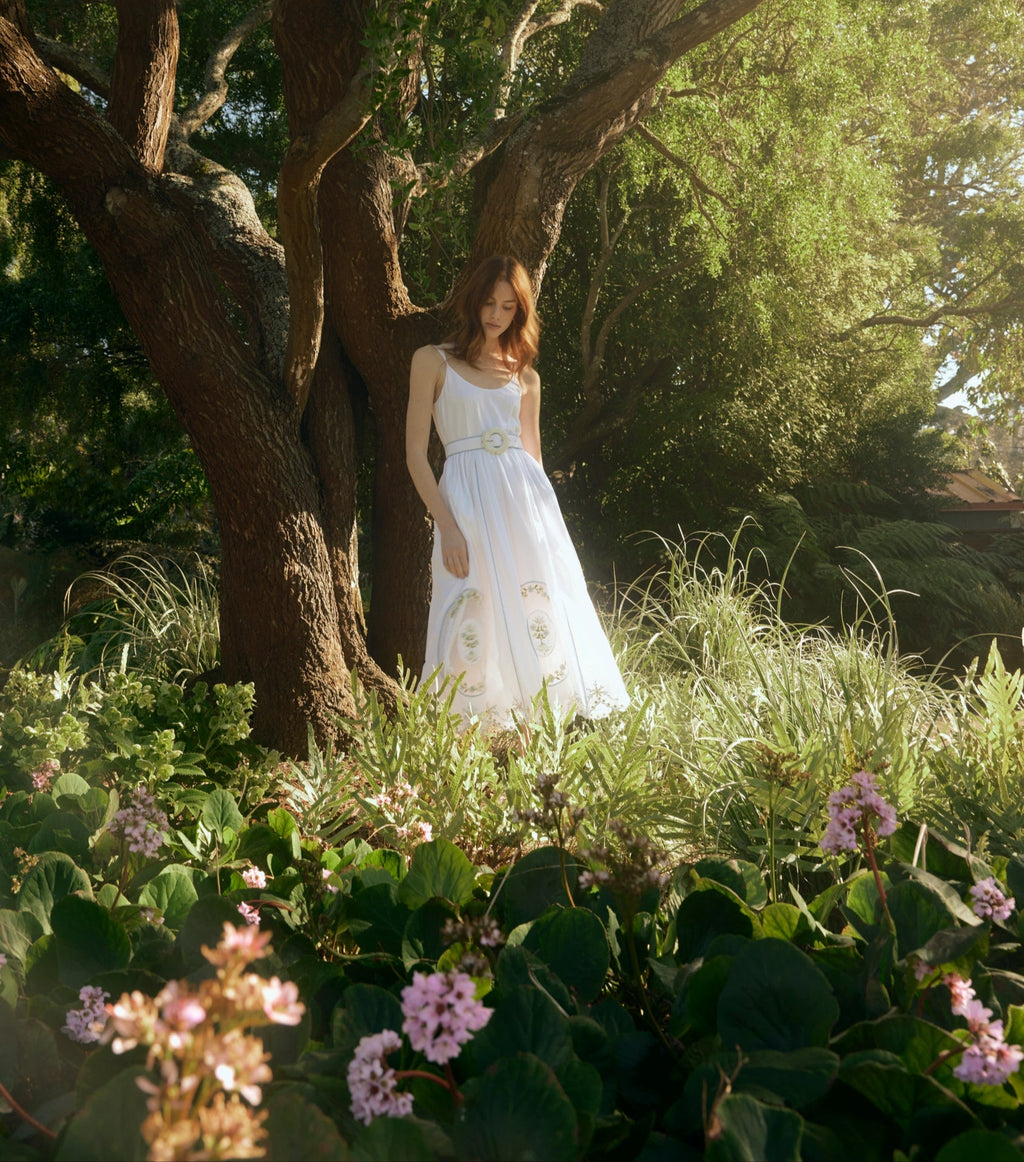 Model wearing Katherine Dress in White Whimsy, embroidered lace dress with fitted bodice and A-line skirt in sunlit garden