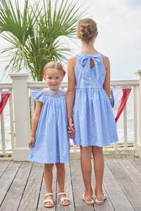 Little English traditional children's clothing. Flutter sleeve dress for toddler girls in royal blue mini gingham with smocking at the collar and American flag bunting