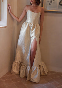 Front view of The Charlotte Dress in Taupe Duchess with strapless corset bodice, high side slit, and gathered ruffle hem