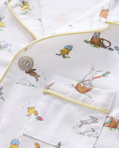 Close-up of the Kids Twill Short Set by Petite Plume in the Easter Frolic print, showcasing whimsical rabbits, birds, and mushrooms. Accented with thin yellow piping, it features a partially visible button and pocket for added charm.