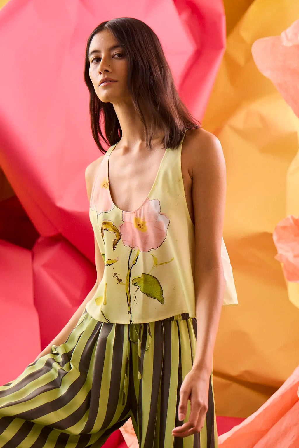 The Carsyn Tank in Quiet Bloom paired with Cyprus Pant in Evergreen Stripe in front of colorful wall.