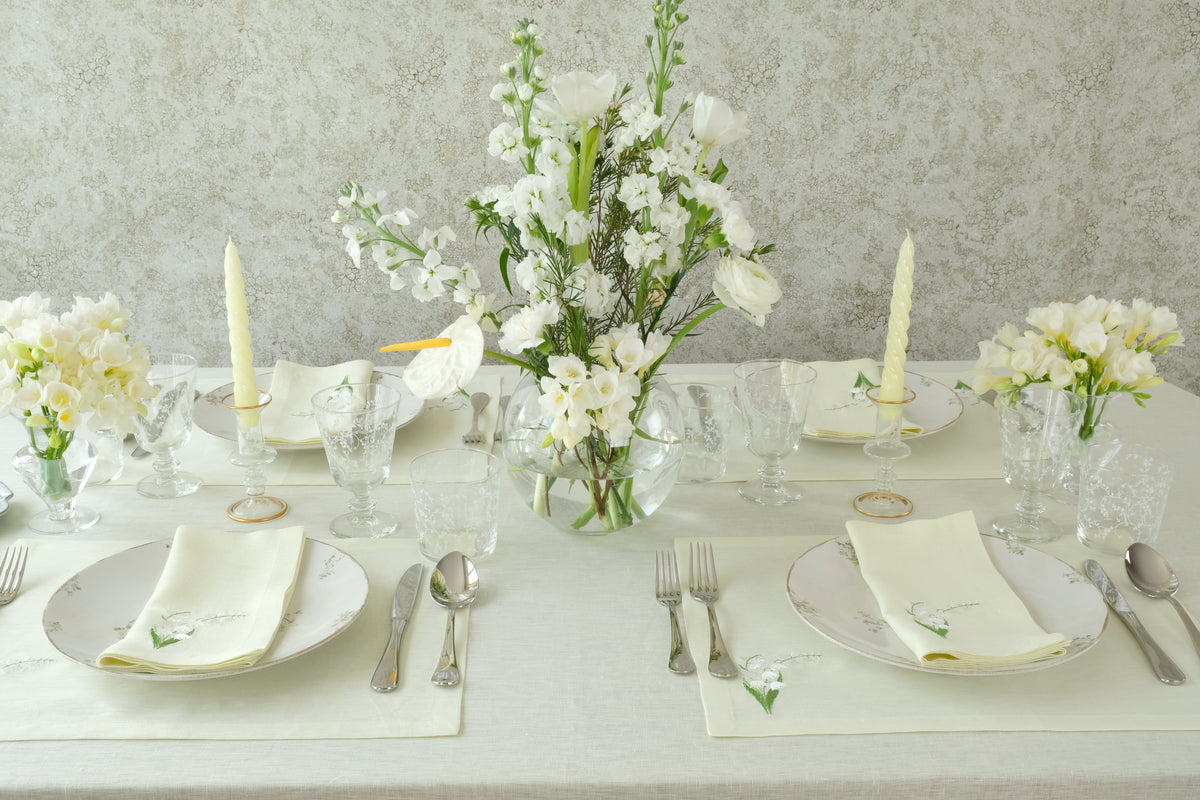 Overhead view of Lily of the Valley napkin and placemat set of 2 showcasing light green linen with delicate white floral embroidery on a styled dining table