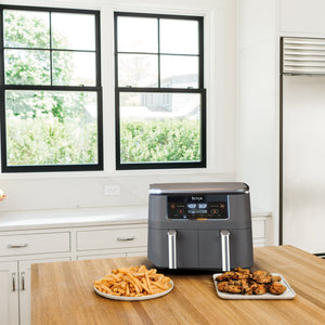 Front view of two-basket 8 qt air fryer with DualZone control panel reading 400F and 360F on a kitchen counter with plates of fries and chicken