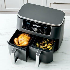 Front view of Ninja Foodi 10 qt XL dual-drawer air fryer showing two baskets with roasted chicken and brussels sprouts