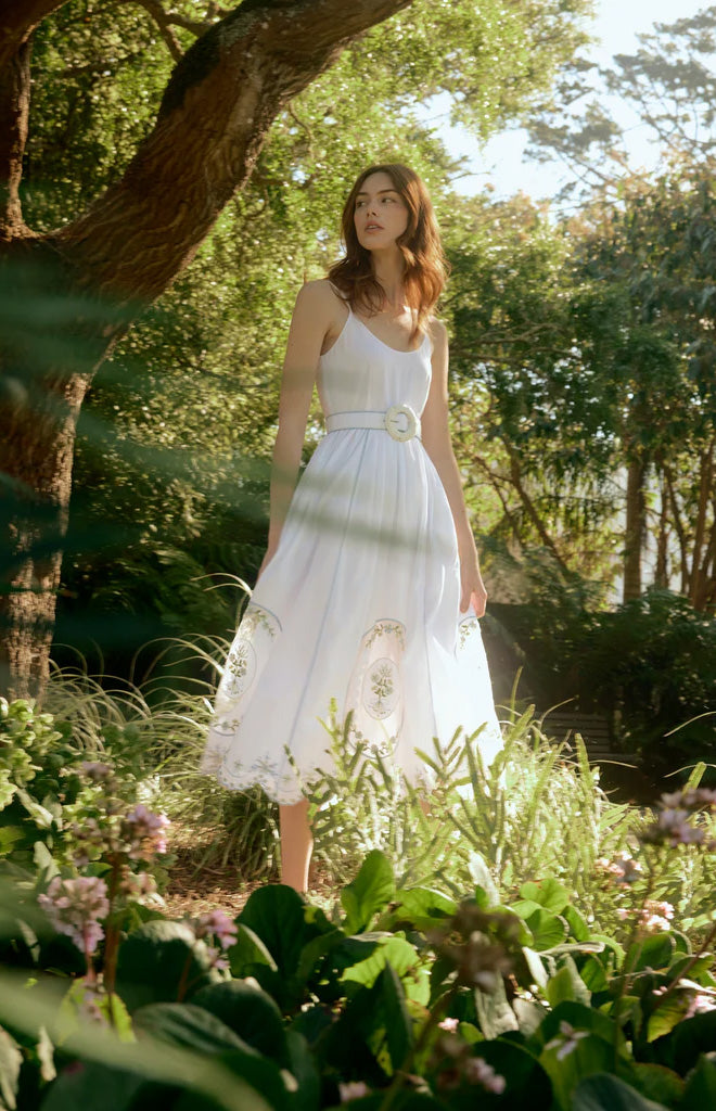 Model standing in sunlit garden wearing Katherine Dress in White Whimsy, fitted bodice and voluminous A-line skirt