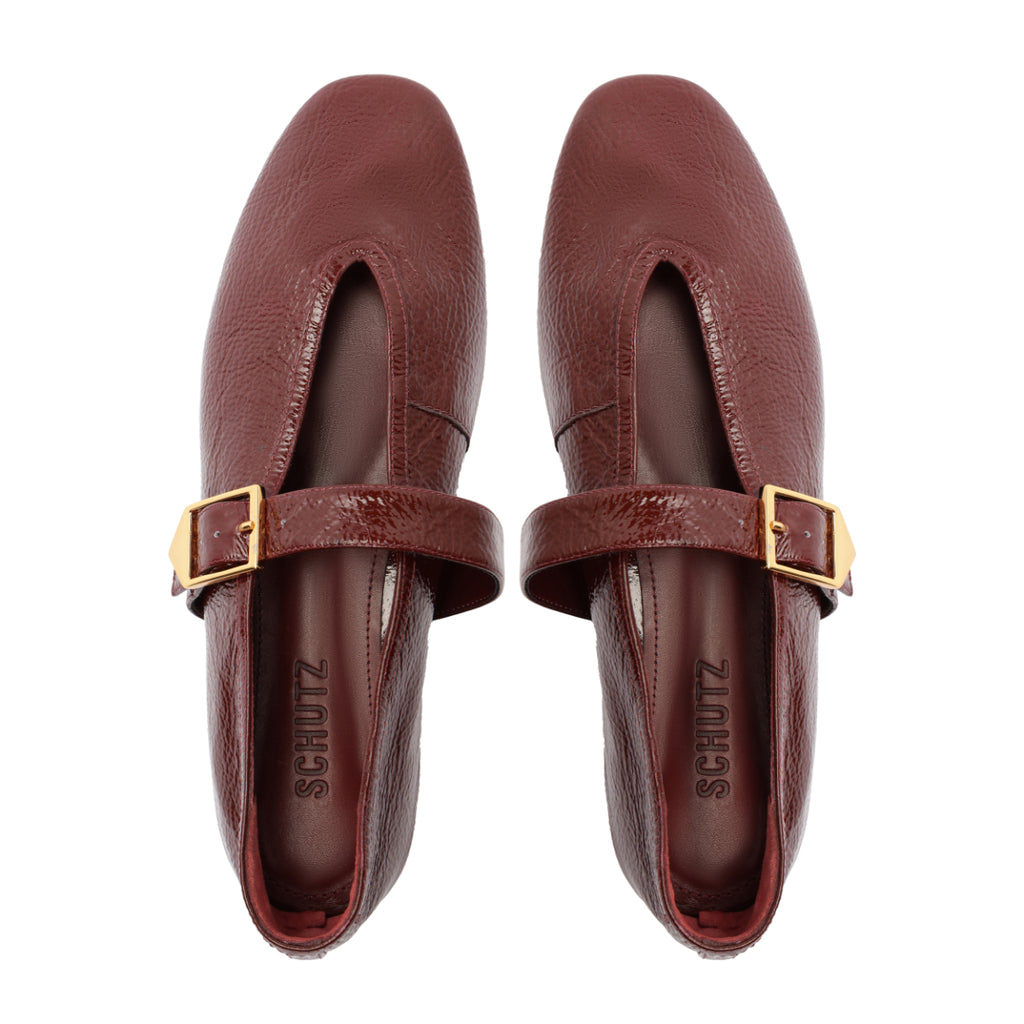 Top view of Courtney Buckle patent flat in vino showcasing square toe, gold buckle strap, and pebbled patent leather on white background