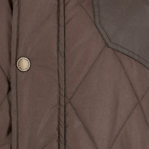 Close-up of the Tom Beckbe Paddock Quilted Jacket with brass snaps and visible stitching, perfect as a weatherproof layer.