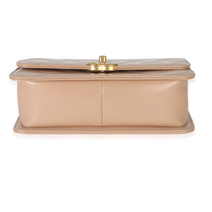Bottom view of Chanel beige quilted calfskin mini Perfect Fit flap bag showcasing champagne gold turnlock on white background