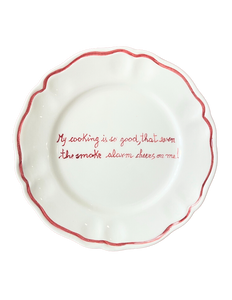 Top view of scalloped ceramic plate showcasing red hand-painted rim and centered handwritten message on black background
