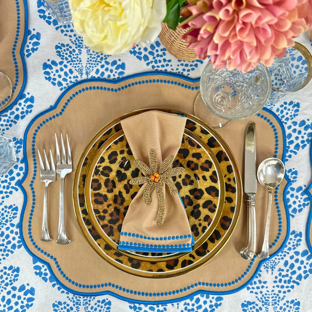 Decorative table setting with leopard print charger, gold rimmed plates, and colorful flowers.