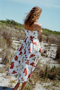 Back view of Skinny-Strap Poof Dress in Red Hibiscus with adjustable straps, fitted waist, and full floral skirt on sand