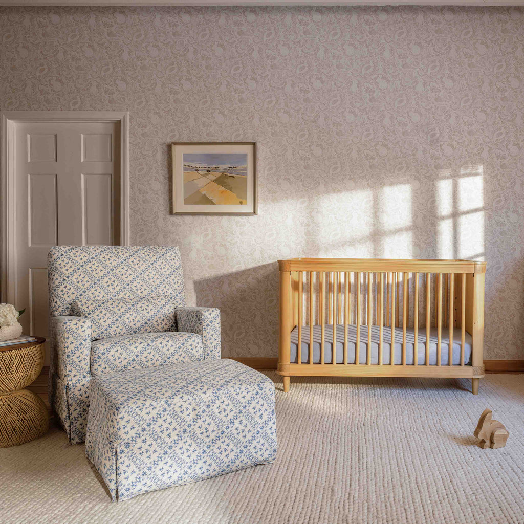 Blue lattice upholstered swivel glider and matching ottoman beside a natural wood crib in a sunlit nursery