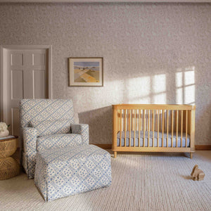 Blue lattice upholstered swivel glider and matching ottoman beside a natural wood crib in a sunlit nursery