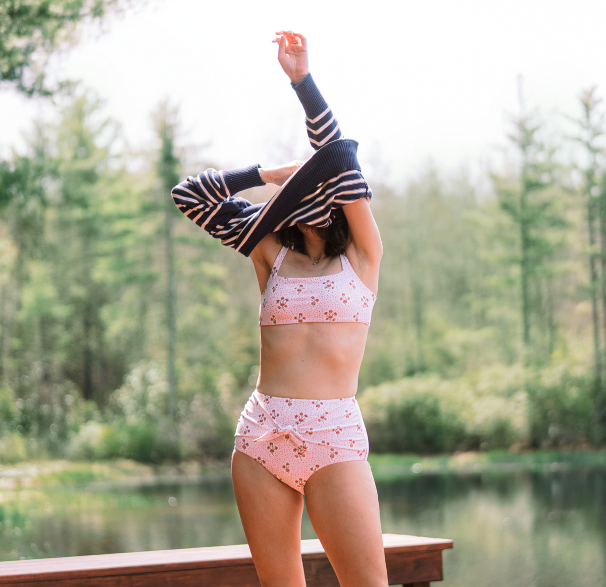 Front view of women’s high-waist bikini bottom showing ruched tie and pink floral print, lakeside background