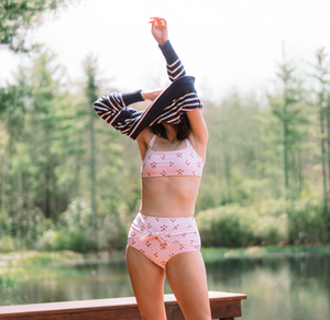 Front view of women’s high-waist bikini bottom showing ruched tie and pink floral print, lakeside background