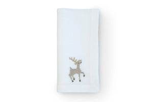 Top-down view of folded white linen napkin showcasing gold sparkling reindeer embroidery on white background